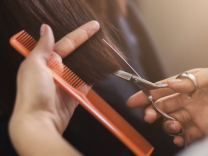 Una peluquera corta el pelo a una clienta.