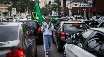 Um vendedor de bandeiras caminha entre os carros em São Paulo.