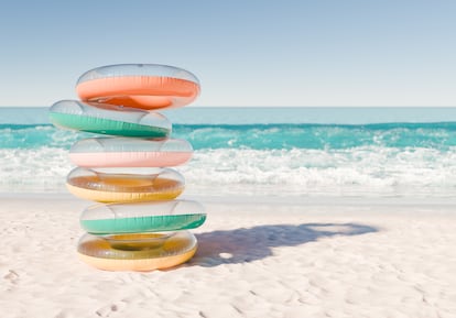 Stack of Colorful Swim Rings on Sunny Beach Shoreline