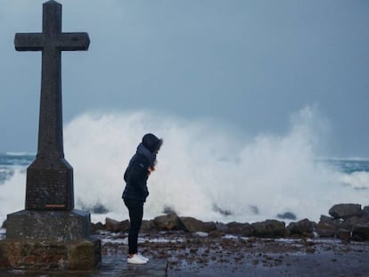 Una mujer junto a una cruz en la costa del desembarco de Normandía.