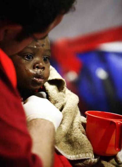 Un voluntario de la Cruz Roja alimenta al niño de año y medio que llegó ayer en un cayuco a Gran Canaria.