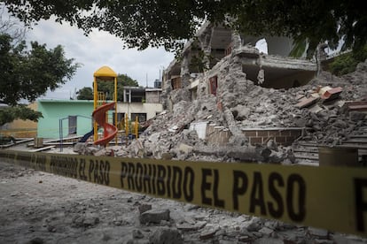 Un edificio colapsado a un costado de una zona de juegos.