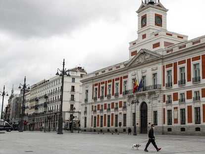 Un hombre pasea con su perro por la Puerta del Sol, junto a la sede del Gobierno de Madrid.