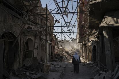 Un hombre camina entre tiendas destruidas en la Ciudad Vieja de Mosul, de las que sólo quedan escombros y amasijos de hierro.