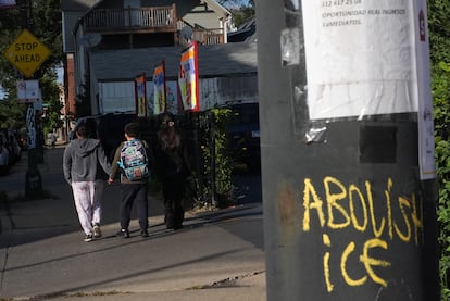 Estudiantes pasan por un poste con un graffiti que aboga por la abolición del ICE en Chicago, Illinois.