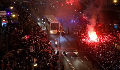 Aficionados contemplan el paso del autobús del Real Madrid a la llegada al estadio Santiago Bernabéu, antes del inicio del partido de ida de octavos de final de Champions League.