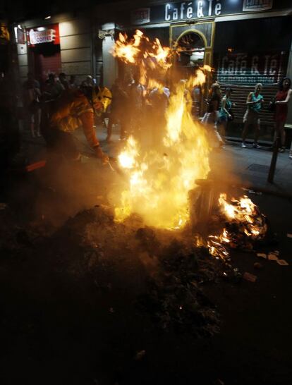 Un operario del Ayuntamiento de Madrid apaga un contenedor de basuras en llamas durante los pequeños enfrentamientos después de la protesta contra las medidas de austeridad del Gobierno en el centro de Madrid.