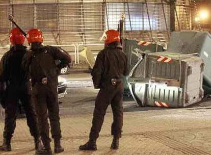 Tres <i>ertzainas,</i> ante contenedores derribados en la manifestación <i>abertzale</i> del sábado en San Sebastián.