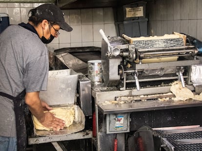 Un hombre produce tortillas en un local.