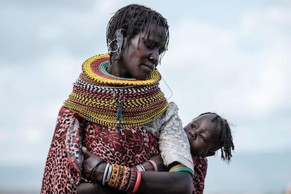 Una mujer turkana adornada con los abalorios tradicionales de su etnia sostiene a su hijo en la espalda durante el festival, que este año ha tenido lugar en Loiyangalani, un pueblo pesquero a orillas del río Turkana.