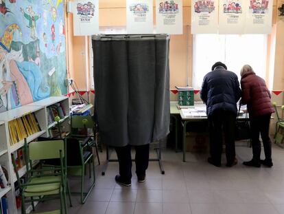 Varios electores escogen su papeleta en el colegio público La Navata, en Galapagar.