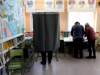 Varios electores escogen su papeleta en el colegio público La Navata, en Galapagar.