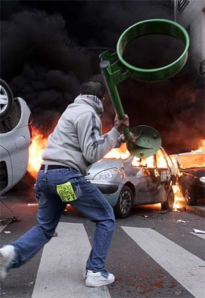 Un hombre lanza una papelera contra un coche en llamas ayer al final de la manifestación de París.