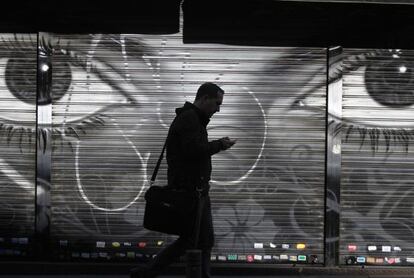 Homem caminha usando celular em uma rua de Madri.