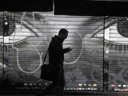 Homem caminha usando celular em uma rua de Madri.