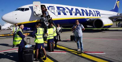 Tripulantes de cabina de pasajeros de Ryanair, a pie de pista, ante un avión de la compañía.