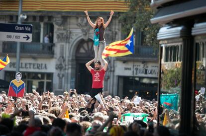 Dos manifestantes en formación de 'castell' al lado de una imagen de Rajoy con la camiseta de Venezuela durante la protesta de Barcelona.