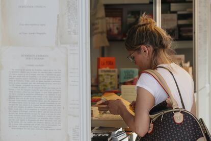 Una mujer lee la contraportada de un libro en la feria del parque del Retiro de Madrid.