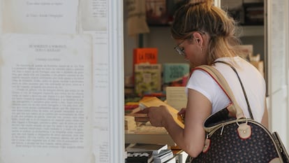 Una mujer lee la contraportada de un libro en la feria del parque del Retiro de Madrid.