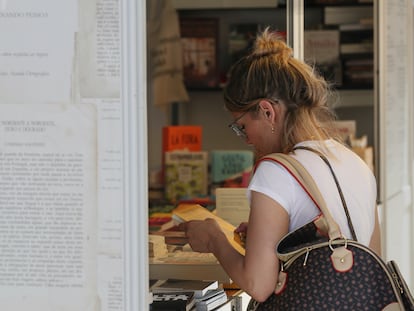 Una mujer lee la contraportada de un libro en la feria del parque del Retiro de Madrid.