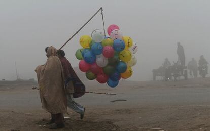 Un vendedor de globos paquistan camina por una carretera en un da de niebla en Lahore (Pakistn).