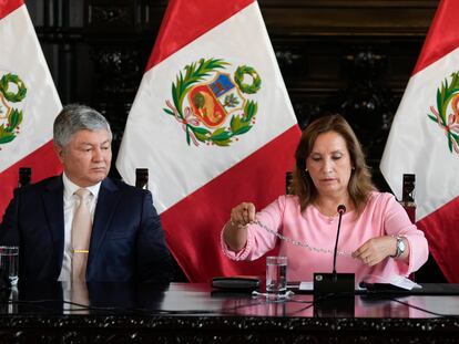 La presidenta de Perú, Dina Boluarte, enseña una gargantilla acompañada de su abogado, Mateo Castañeda, durante una conferencia de prensa.