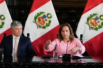 La presidenta de Perú, Dina Boluarte, enseña una gargantilla acompañada de su abogado, Mateo Castañeda, durante una conferencia de prensa.