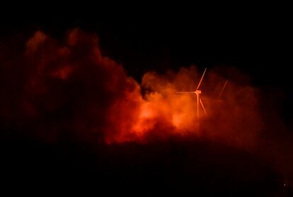 Las llamas del incendio alcanzan las turbinas eólicas en la cima de una montaña en el Parque Natural del Moncayo, en la región norte de Aragón, visto desde la ciudad de Borja.