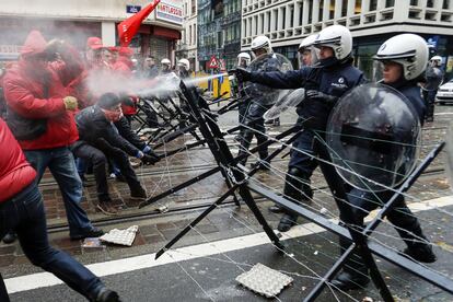 La policía rocía con gas lacrimógeno a unos manifestantes durante la huelga general en Bruselas.