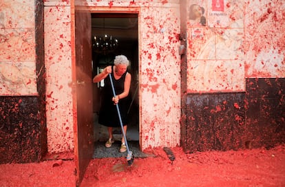 Una mujer limpia el suelo exterior de su puerta, cubierto de tomate tras la fiesta de la Tomatina de este miércoles.