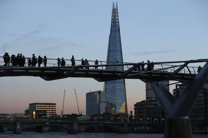 El edificio Shard al atardecer observado por turistas que cruzan el puente del Milenio en Londres.