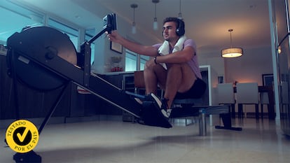 Un chico en su casa entrenando con la máquina de remo.
