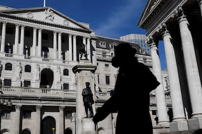 Una persona con máscara camina frente al edificio del Banco de Inglaterra