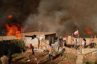 Varios residentes observan el fuego acercándose, mientras trabajan para que no se extienda a las casas.