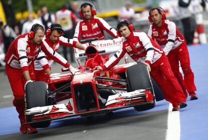 Los mecánicos de Ferrari empujan el coche de Alonso.
