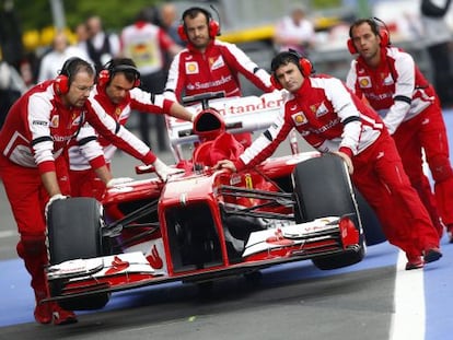 Los mecánicos de Ferrari empujan el coche de Alonso.
