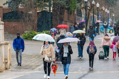 Varias personas caminan bajo la lluvia la mañana de este lunes en Teruel.