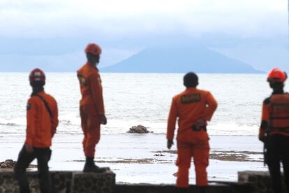 Miembros de los servicios de rescate observan el volcán Anak Krakatau desde la playa Carita, en Indonesia.