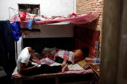 Worker Shi Shenwei (L) uses his phone in a colleague's room in an old farm house in the village of Huangshan, near Quanzhou, Fujian Province, China, September 28, 2016. Shi had to vacate his room after heavy rain leaked through the roof and wet his mattress. REUTERS/Thomas Peter         SEARCH "BRICK CARRIER" FOR THIS STORY. SEARCH "WIDER IMAGE" FOR ALL STORIES. 