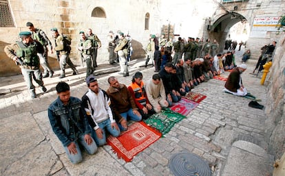 Unos hombres musulmanes rezan en presencia de unos soldados israelíes cerca de la Puerta del León en la Ciudad Vieja en Jerusalén.