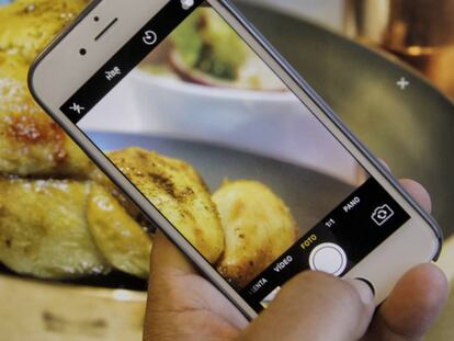 Una persona fa una fotografia amb el seu mòbil a un plat de menjar.