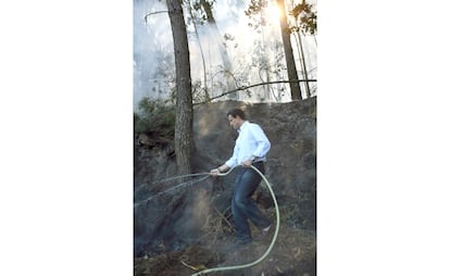 VGO13. Meis (Pontevedra), 08-08-06.- El Presidente del PPdeG Alberto Nuñez Feijoo, cogió la manguera para ayudar a sofocar un fuego que se acercaba a una casa en Cabeza de Boi (aldea del concello de Meis), una de las localidades más afectadas por la ola de incendios que desde hace cinco días arrasa Galicia, que ha visitado hoy junto al presidente del PP, Mariano Rajoy. EFE/Salvador Sas