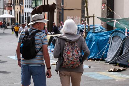 Dos turistas caminaban el lunes frente al campamento improvisado instalado por activistas que realizar una huelga de hambre para exigir al Gobierno de Canarias que paralice la construcción de dos proyectos urbanísticos en el sur de Tenerife, en la plaza de la Concepción en La Laguna.