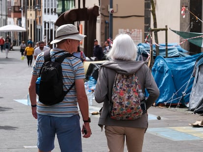 Dos turistas caminaban el lunes frente al campamento improvisado instalado por activistas que realizar una huelga de hambre para exigir al Gobierno de Canarias que paralice la construcción de dos proyectos urbanísticos en el sur de Tenerife, en la plaza de la Concepción en La Laguna.