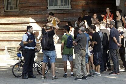 Un mosso d'esquadra parla amb les persones que s'han reunit al col·legi Collaso i Gil de Barcelona.