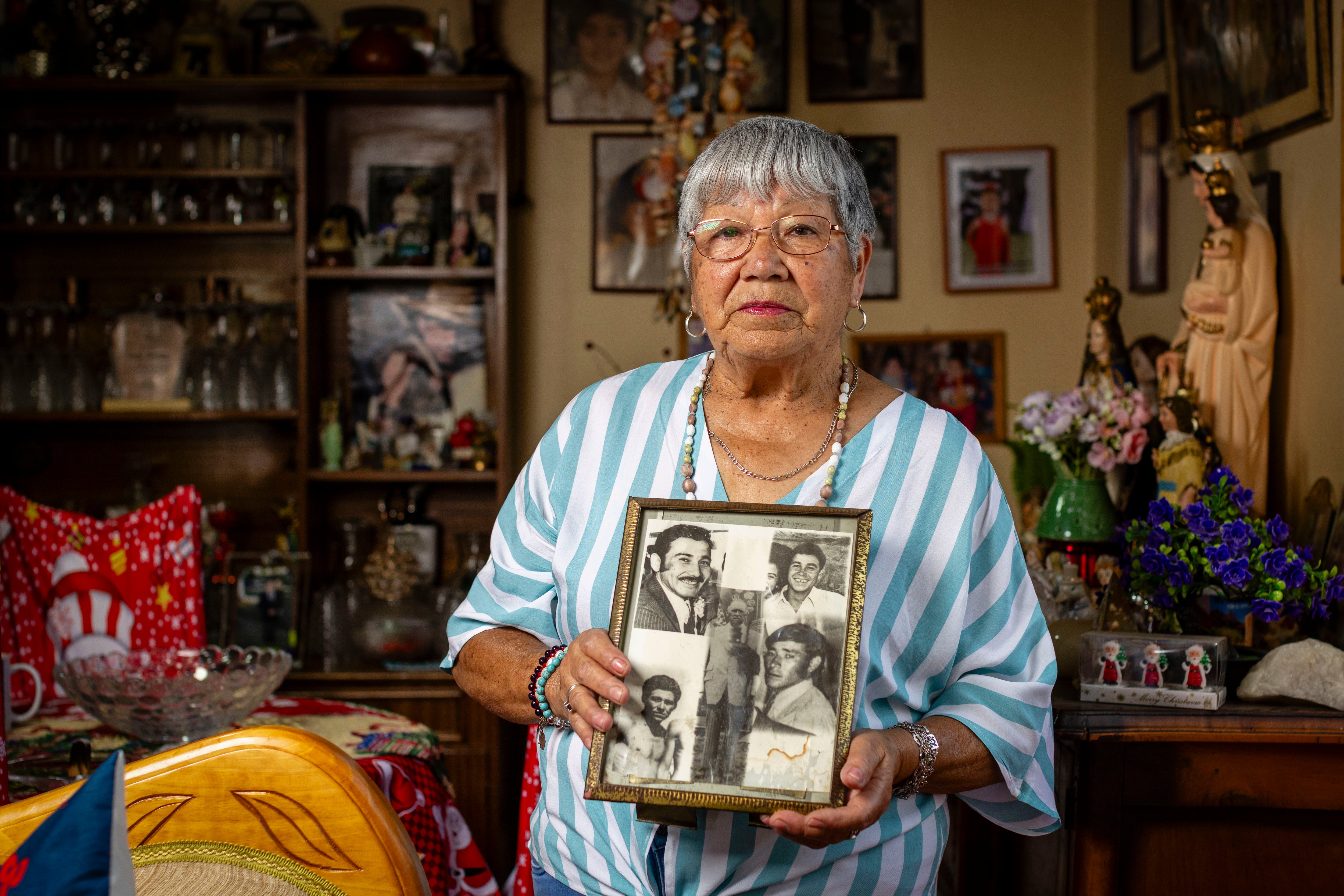 Corina Maureira con un cuadro con las fotografías de sus cuatro hermanos y su padre, víctimas de desaparición forzada durante la dictadura, en Isla de Maipo (Chile), el 19 de diciembre.