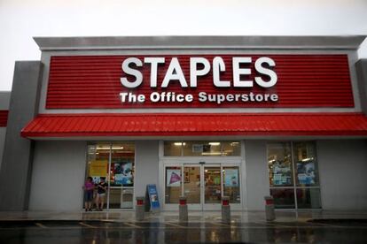 Dos mujeres se resguardan de la lluvia en una tienda en Miami de Staples, la cadena que acaba de anunciar el cierre del 12% de sus establecimientos. 