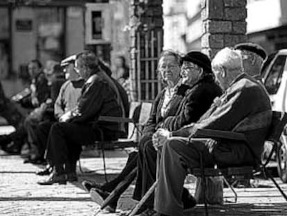 Varios ancianos toman el sol en los bancos de la plaza del pueblo de Ponteareas (Pontevedra).