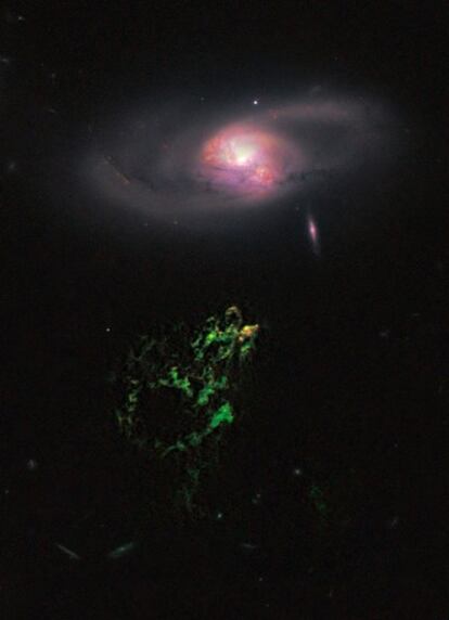 El Objeto de Hanny parece flotar debajo de una galaxia espiral, en esta imagen tomada por el telescopio <i>Hubble</i>, en la que se observa en el extremo superior de la nube verde la región de formación de estrellas.