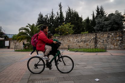 A mother transports her son by bicycle at dawn in Bogotá.